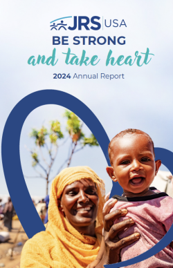 2024 JRS/USA Annual Report Cover | Be Strong and Take Heart. A picture of a mom holding her baby up to the caera while smiling. There is a blue heart intertwined between the both of them.